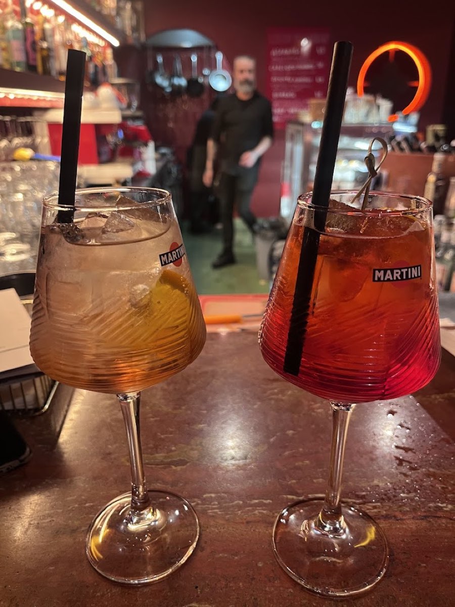 Dwa spritze w falowanych kieliszkach na ladzie baru, w tle barman